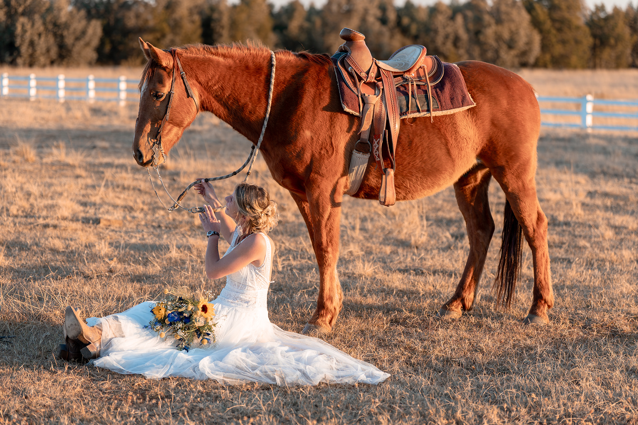 Bride sitting on the ground with her horse