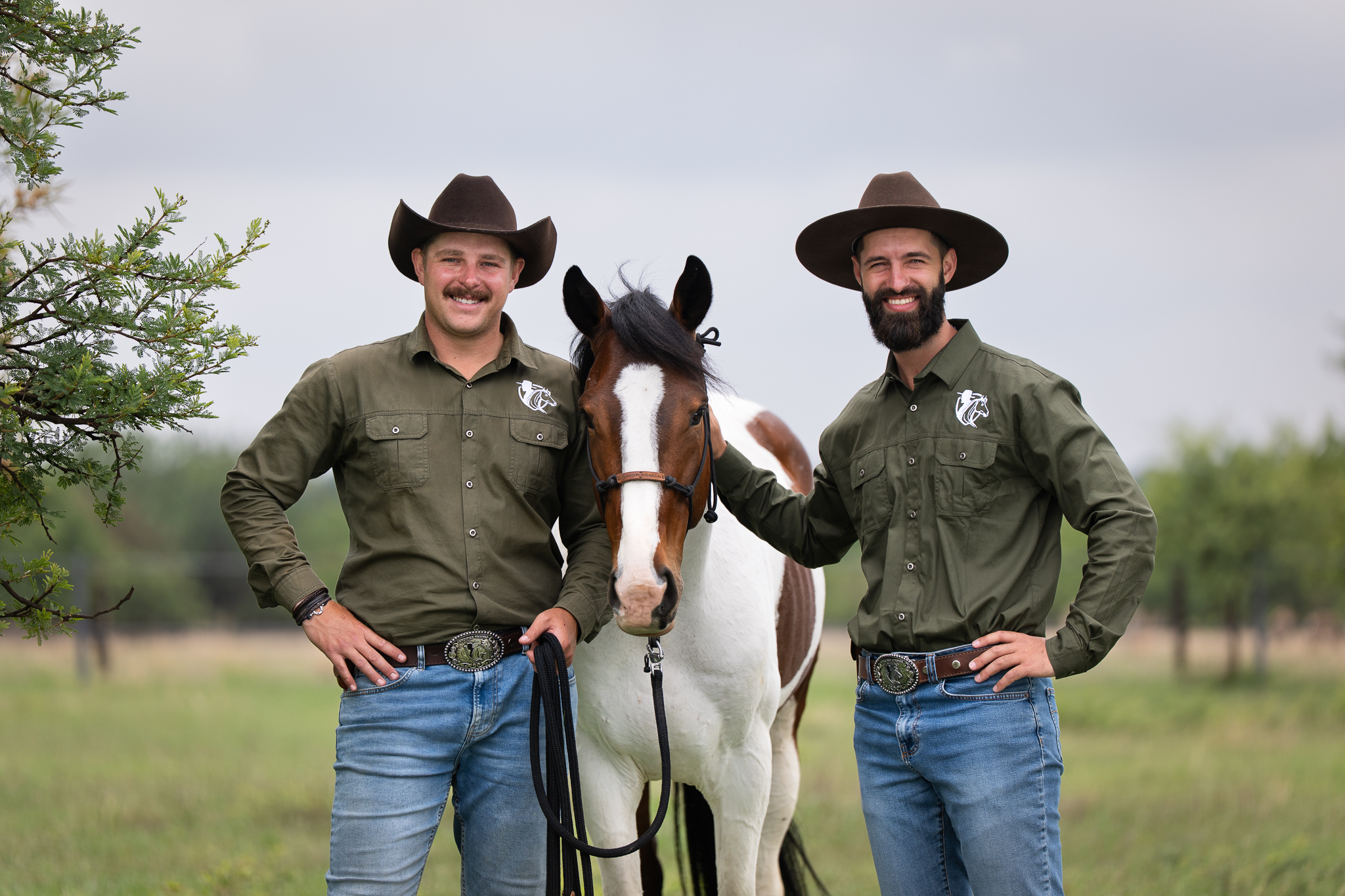 Portrait of two Smith Horsemanship trainers posing with a horse