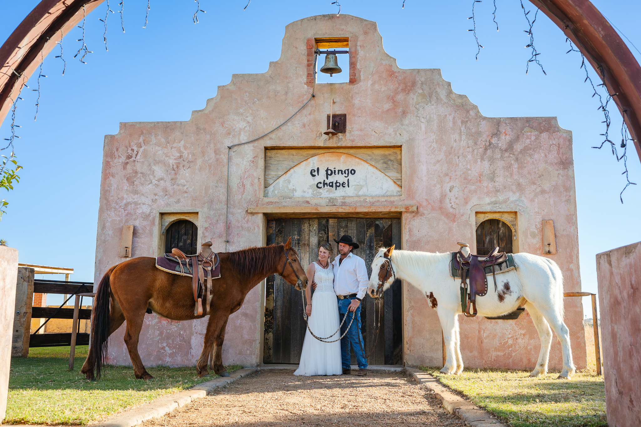 Bride and groom posing with horses at the chapel