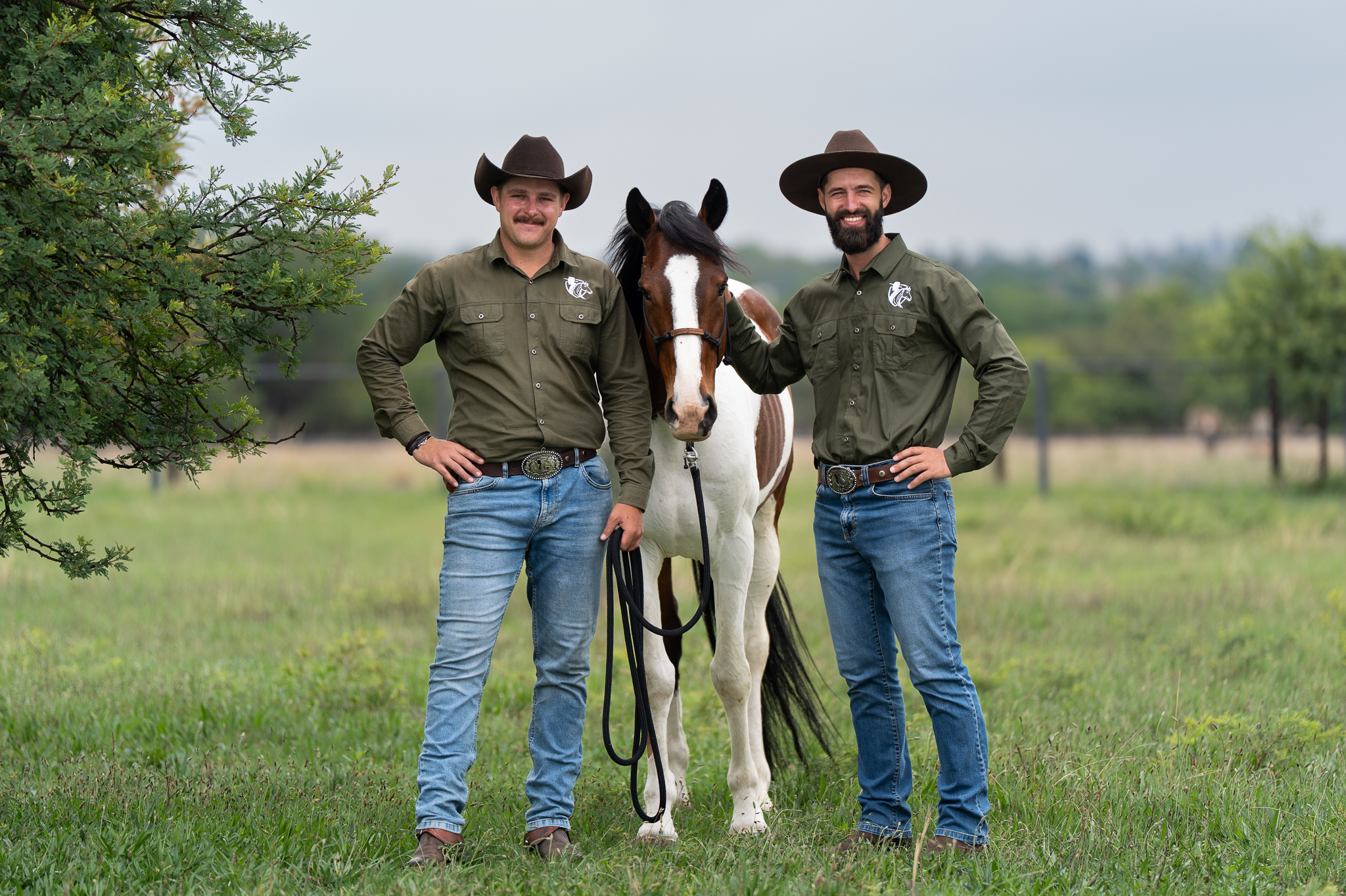 Portrait of two Smith Horsemanship trainers posing with a horse