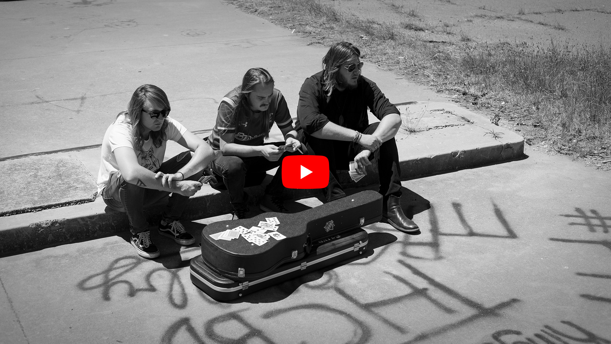 Black and white image of band members with cards and guitar case