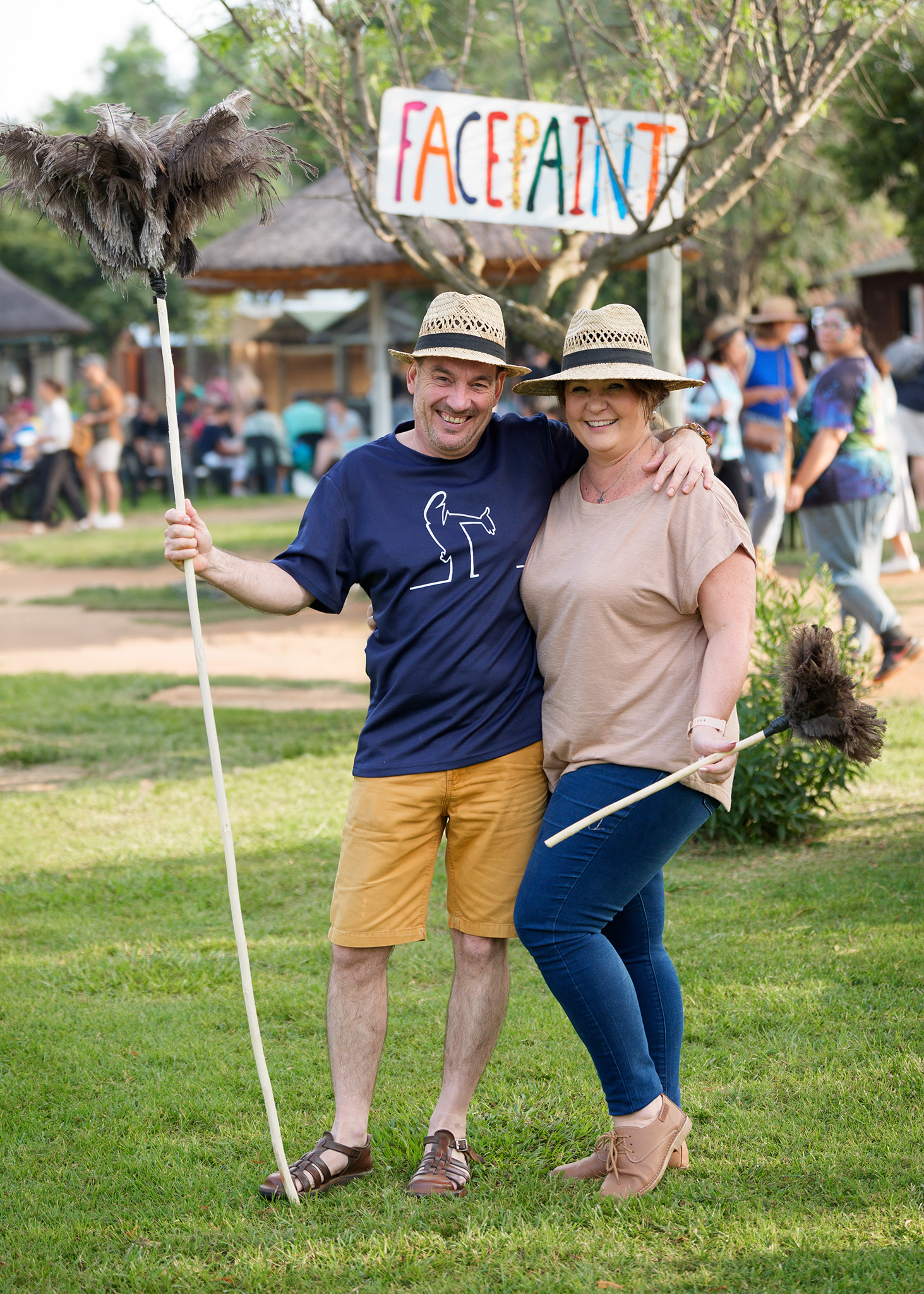 A fun Couple pose for the camera with feather dusters at the Pretoria Boeremark