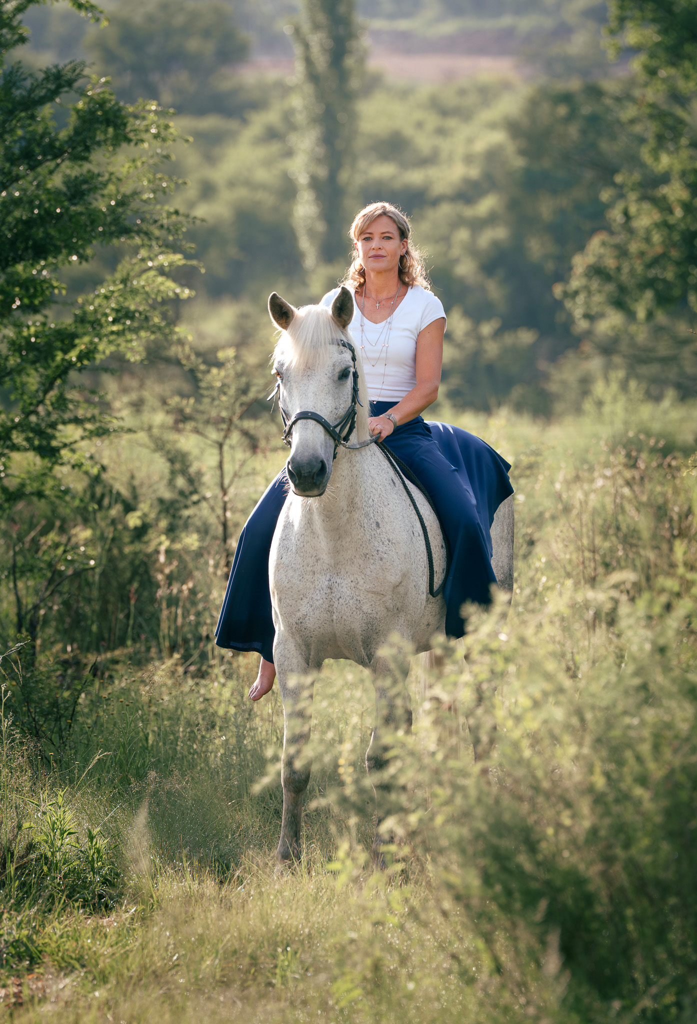 Regal portrait of a lady riding her grey horse in nature