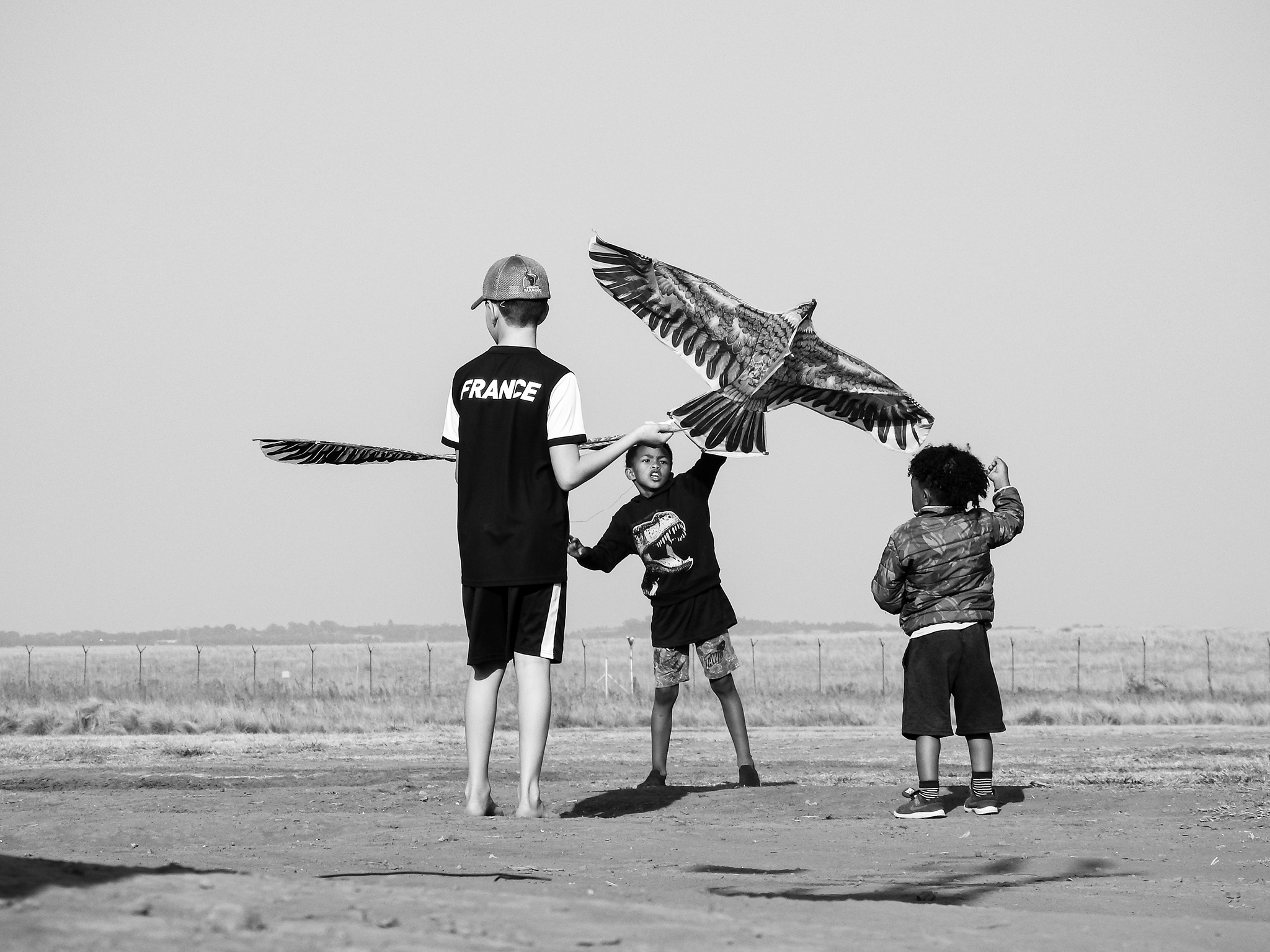 Black and white image of children playing with a kite