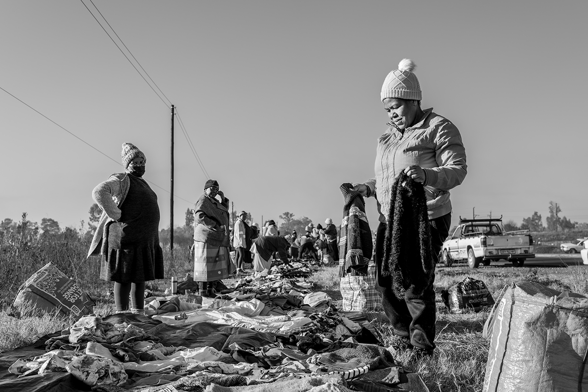Black and white image of street vendors selling clothes