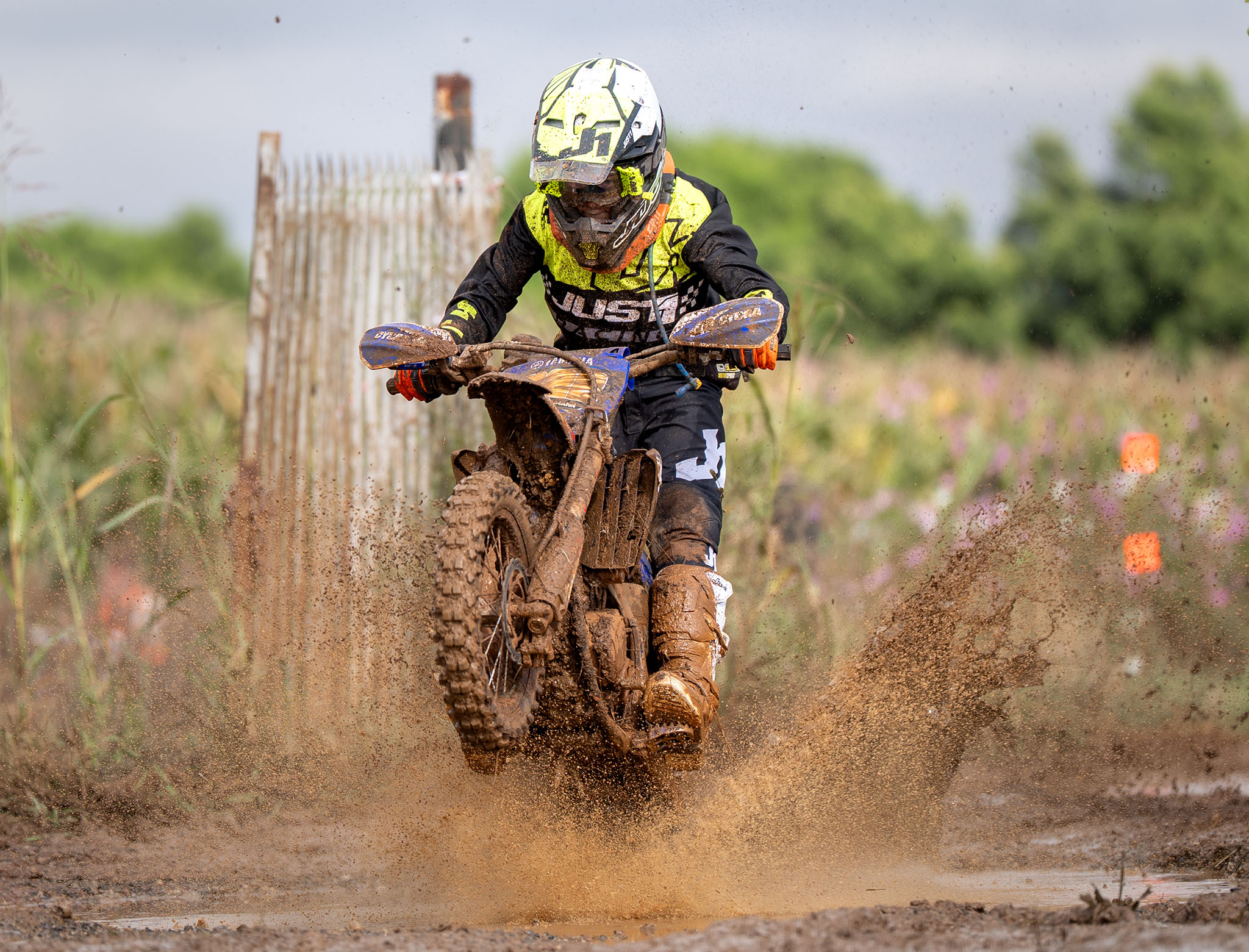 A junior rider splashes through the mud at a moto x country event